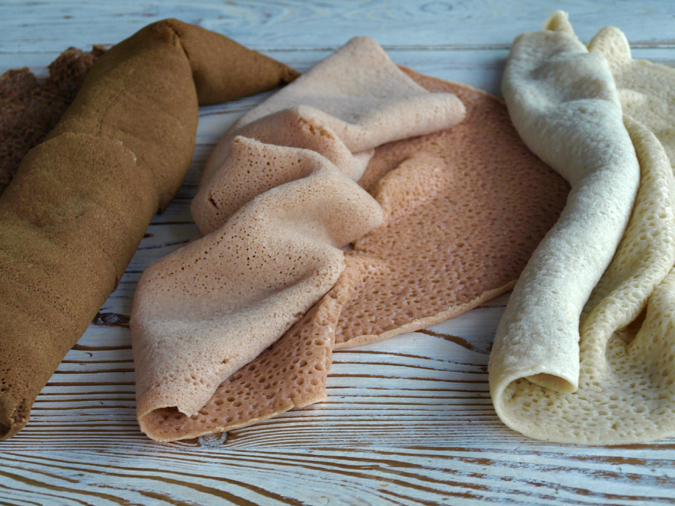 Injera in three colours - wheat (white), sorghum (pink) and teff (brown)