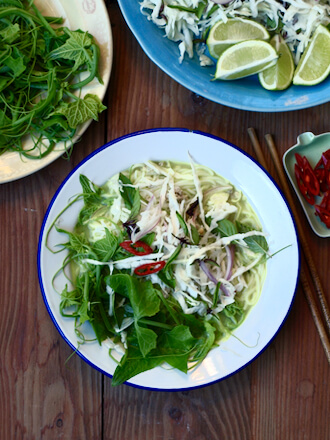Bowl of Laos-style fish soup with rice vermicelli, choko (chayote) shoots, cabbage and herbs
