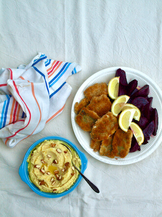 Plate of crumbed sardines, beetroot and lemon wedges with a bowl of Greek skordalia mayonaisa